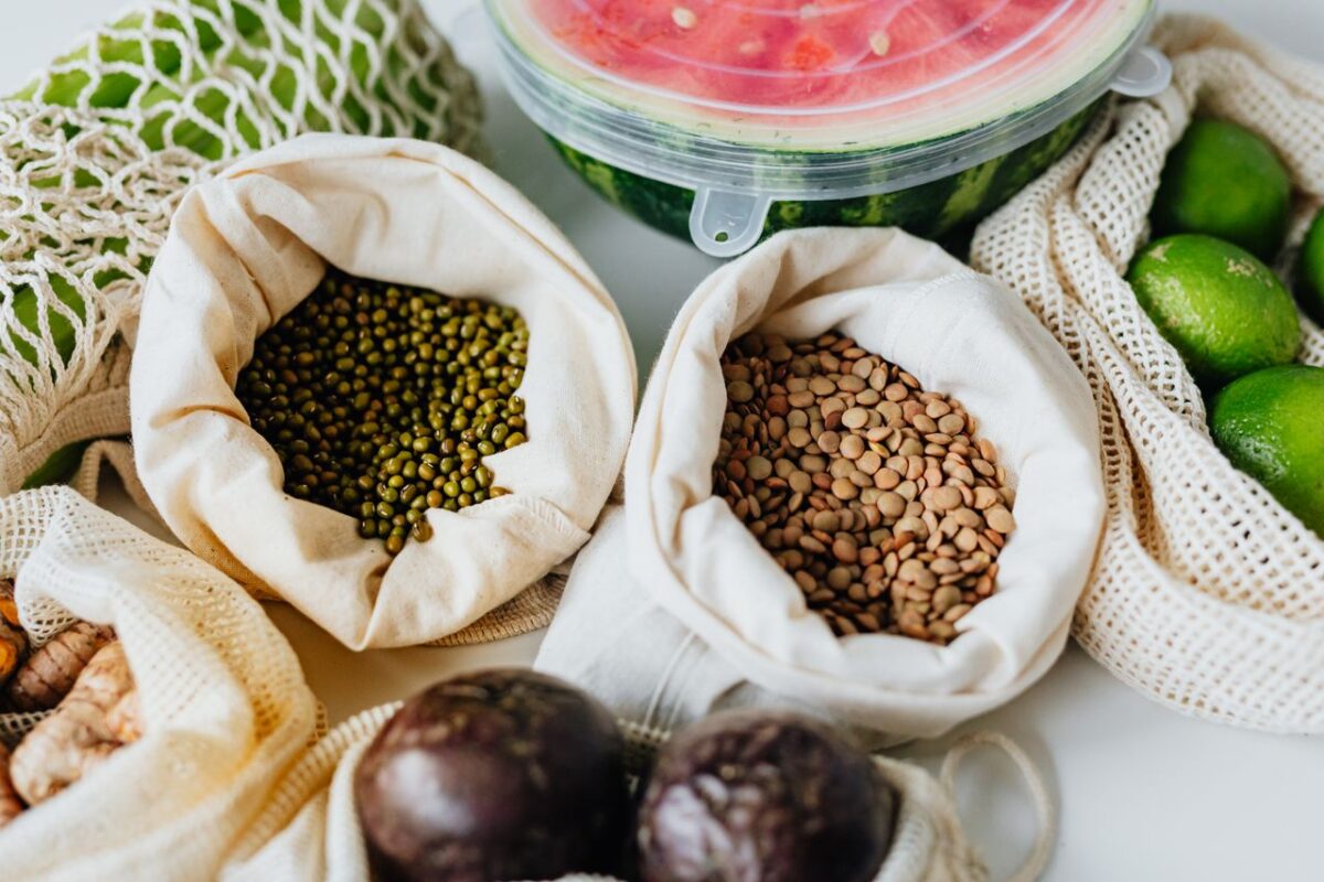 Assorted sustainable produce and grains in reusable bags promoting eco-friendly living.